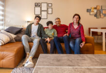 Father’s search for diagnosis leads to innovative AI breakthrough A family of four at home sit on a sofa looking at the camera.