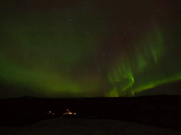 NASA Plans Triple Rocket Launch from Alaska for Aurora Study A time-lapse of auroral activity looks like green, red, yellow, and orange curtains traveling across a clear night sky filled with stars. In the dark land below, faraway launch pads are lit by floodlights, and two tiny vertical rockets can be seen waiting for launch.