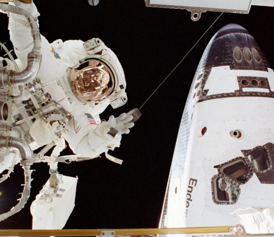 Astronaut John Herrington Completes Spacewalk Mission – NASA An astronaut in a white spacesuit appears on the left side of the image near a part. On the right in the back is part of the space shuttle Endeavour.