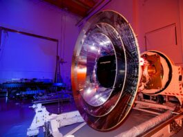 NASA Opens Media Access for Cosmic and Solar Missions Launch The large, shiny silver, round SPHEREx telescope sits in a room lit by blue and orange lighting.