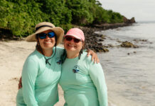 Interview: OCEANOS Instructor María Fernanda Barbarena-Arias – NASA Two Puerto Rican women stand on a beach, both wearing teal longsleeve shirts and sunglasses. The one on the left has a tan, wide-brimmed hat, and the one on the right has a pink baseball cap.