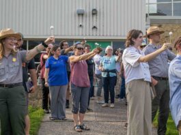 Urban Parks Link Communities to Space Science through NASA Training A group of people stand outside holding white Styrofoam balls on a stick with arms outstretched to model moon phases.