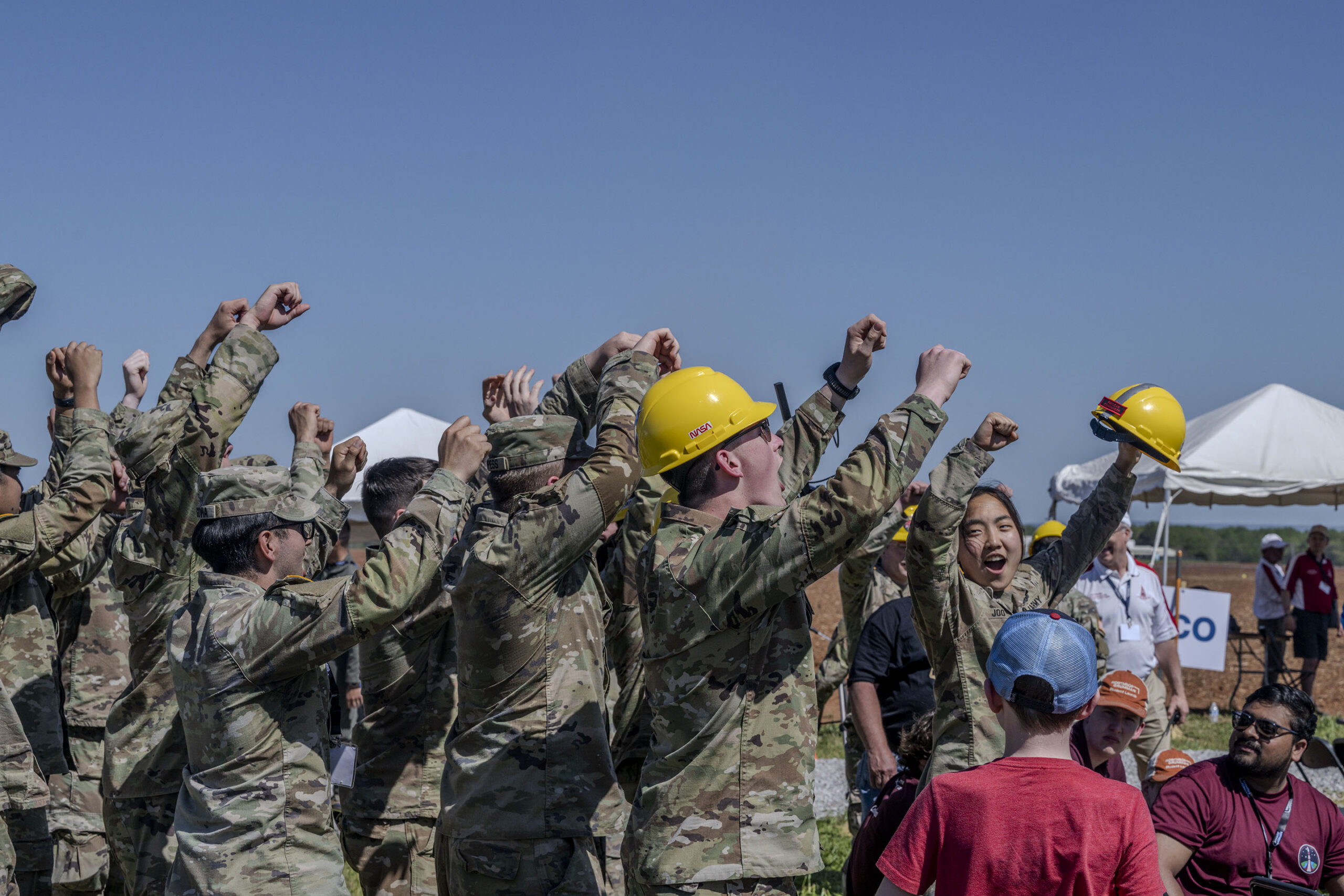 Students raise their hands in celebration and cheer after a successful launch of their vehicle in the 2024 Student Launch competition.
