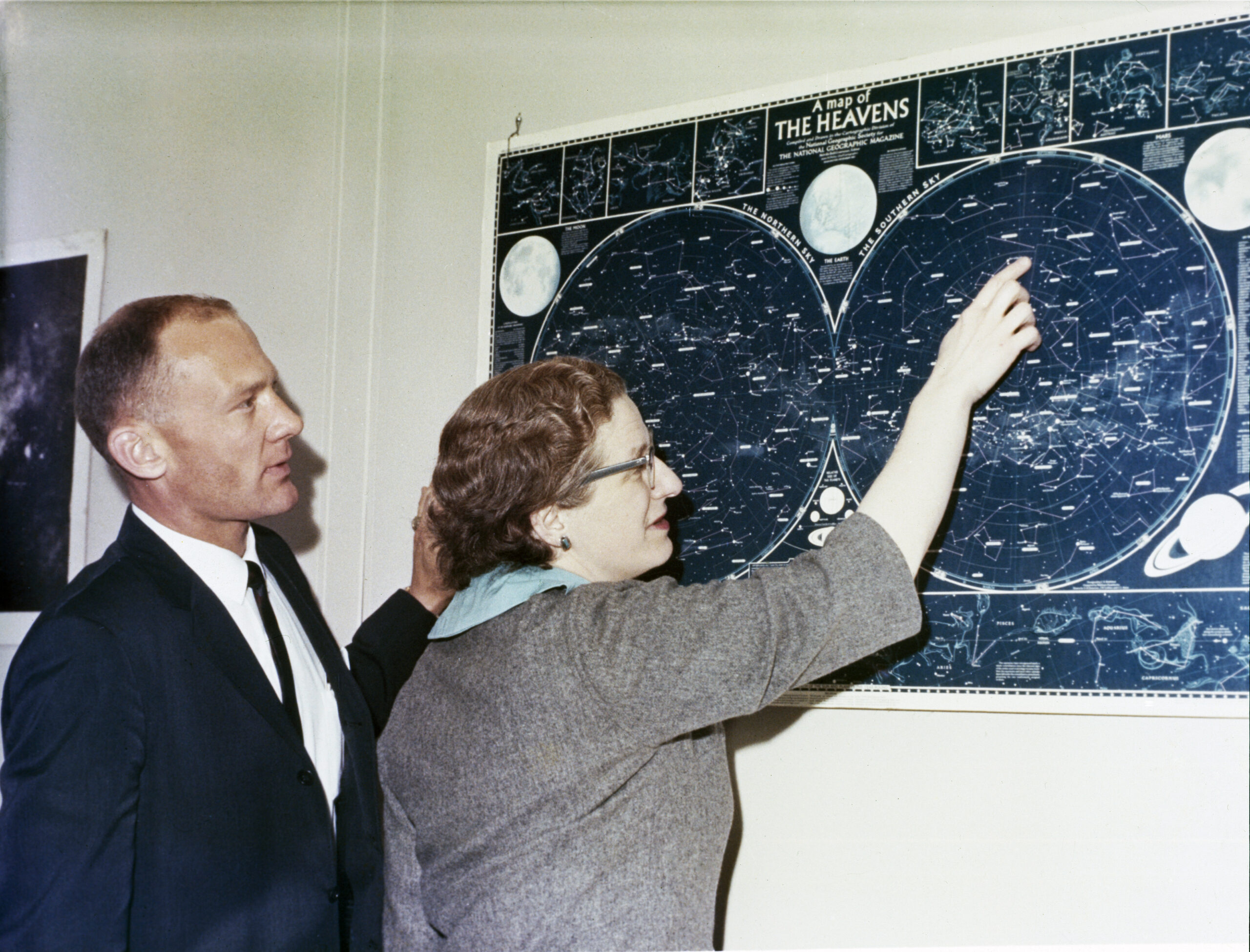 41304996754 d135f524b1 o.jpg Two people - astronaut Buzz Aldrin and Dr. Nancy Grace Roman - look at a map of celestial objects hanging on a wall in front of them. The photos is taken from the side, so their profiles are visible. Aldrin wears a dark suit and tie, while Roman wears a gray short sleeved jacket. She is pointing at a constellation on the blue and white map.