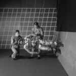 NASA Breaks Barriers with Anti-Gravity Innovations In this black and white photo, two people adjust a 1960s-era spacesuit on a person who is suspended by wires. This third person is parallel to the floor, with his feet on the wall on the right.
