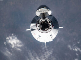 NASA Announces Axiom Mission 4 Launch and Station Arrival Coverage A white spacecraft faces the camera with its nose cone open, with Earth in the background.