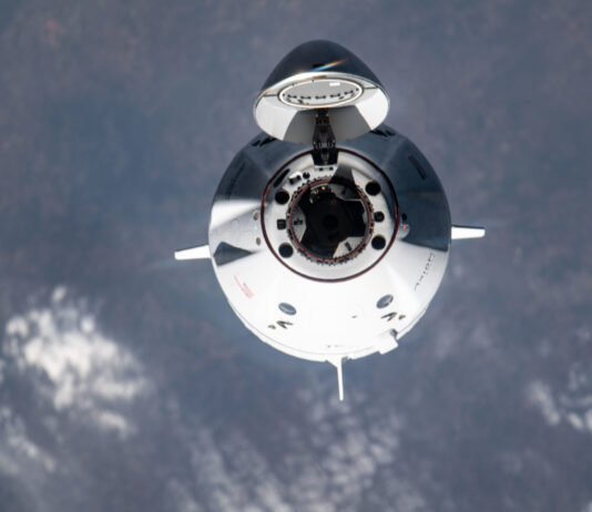NASA Announces Axiom Mission 4 Launch and Station Arrival Coverage A white spacecraft faces the camera with its nose cone open, with Earth in the background.