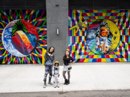 NASA Revives Art Program with NYC Mural in 2024 Two adults and a child pose for a photo in front of a colorful space-themed mural. The child wears an astronaut costume.