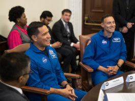 NASA Astronauts Rubio, Berrios Discuss Hispanic Heritage Month Two Hispanic men in blue jumpsuits with NASA patches on them sit at a table, smiling at people off screen. There are people of different ethnicities in the background.
