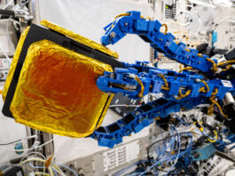 NASA’s Robot Achieves New Milestone in Dexterity Blue tentacle-like arms grip onto a black cube with gold foil patches on it.