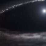 NASA’s Webb Telescope Discovers Frozen Disk An illustration of Sun-like star HD 181327 and its surrounding debris disk. The star is at top right. It is surrounded by a far larger debris disk that forms an incomplete elliptical path and is cut off at right. There’s a huge cavity between the star and the disk. The debris disk is shown in shades of light gray. Toward the top and left, there are finer, more discrete points in a range of sizes. The disk appears hazier and smokier at the bottom. The star is bright white at center, with a hazy blue region around it. The background of space is black. The label Artist