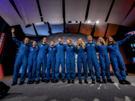 New Group of Astronauts Selected by NASA Ten people in blue jumpsuits link arms. The two women on either end wave at the audience, who is not visible.