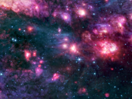 Sagittarius B2 Cloud Explored by NASA Cosmic clouds of pink and purple, some with bright centers, are surrounded by dark areas that appear like black space dotted with bright blue stars. A group of small clouds to the right is more red than any other area of the image.