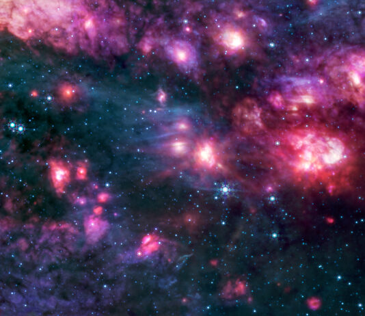 Sagittarius B2 Cloud Explored by NASA Cosmic clouds of pink and purple, some with bright centers, are surrounded by dark areas that appear like black space dotted with bright blue stars. A group of small clouds to the right is more red than any other area of the image.