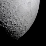 NASA Explores New Frontiers in Light Research Part of the Moon stands out against the blackness of space. Its surface is marked with many craters of different sizes. The craters are mostly on the left and bottom. The upper right portion of the Moon