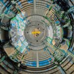 NASA’s Gateway: Deep Space Connectivity Achieved As we look through a circular piece of Gateway, a space station that will be in lunar orbit, there are blue wires snaking through. The wires are covered in clear plastic in some places and held onto the walls by green tape in others.