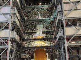 Aaron Rose Leads NASA’s Cold Stowage Mission at Station Nation A man poses in front of a large rocket inside of a facility.