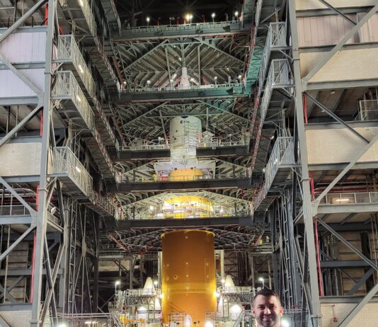 Aaron Rose Leads NASA’s Cold Stowage Mission at Station Nation A man poses in front of a large rocket inside of a facility.