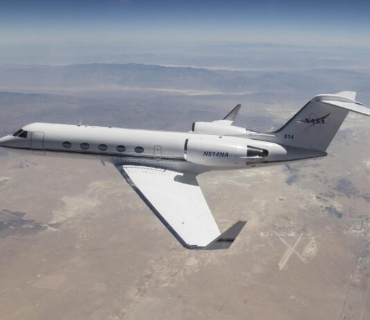 NASA G-IV Aircraft to Test Advanced Science Instrumentation A white Gulfstream IV airplane flies to the left of the frame over a tan desert landscape below and blue mountain ranges in the back of the image. The plane’s tail features the NASA logo, and its wings have winglets. Visible in the lower right third of the image, directly behind the airplane’s wingtip is the Mojave Air and Space Port in Mojave, California.