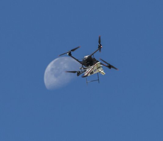 NASA Test Flight Success for Atmospheric Probe An atmospheric probe model carried by a quad rotor aircraft rises and the Moon is visible.