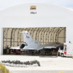 NASA Begins Testing with X-59’s Engine Ignition A white airplane sits inside of a white hangar with its nose facing inward.