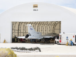NASA Begins Testing with X-59’s Engine Ignition A white airplane sits inside of a white hangar with its nose facing inward.