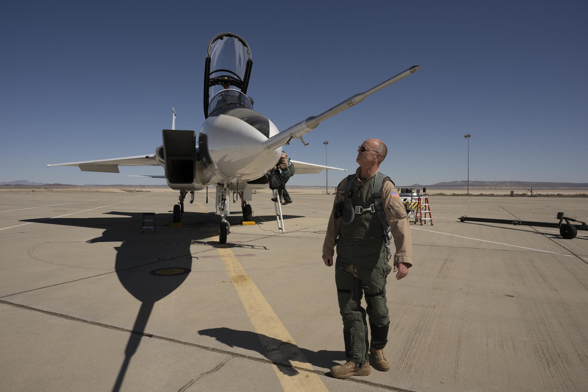 afrc2025 0041 27large.jpg NASA test pilot Nils Larson, wearing a green flight suit and sunglasses, stands at the front of the agency’s F-15D research aircraft, looking up at a long, newly installed shock-sensing probe mounted on the nose. The aircraft is parked on the flightline at NASA’s Armstrong Flight Research Center in Edwards, California, with its canopy open and ladder down.