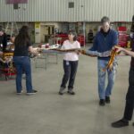 NASA Analyzes Lunar Light to Enhance Earth Monitoring A team of people carry a science instrument across a hangar floor. Two men at the back left of the frame roll a cart carrying the instrument body while four others ahead of the cart walk toward the right of the frame carrying a heavy twine of cables attached to the instrument.