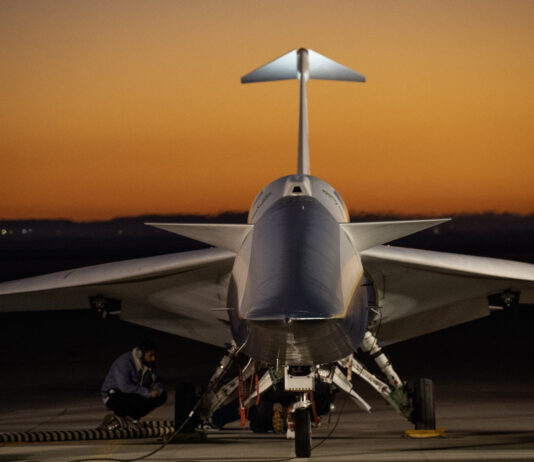 NASA’s X-59 readies for second takeoff mission. An aircraft resting on a section of runway as seen from the front, with its nose facing the camera. The early morning sky is orange in the background.