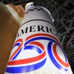 NASA’s Lunar Rocket Marks 250 Years of U.S. Ingenuity Image shows the America 250 logo in black, red, blue colors painted on the white solid rocket boosters of NASA