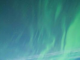 NASA Encourages Aspiring Scientists with Eclipses and Auroras A group of 13 people standing together on snow-covered ground, dressed in warm winter clothing, with the aurora glowing in the sky above them. Some are kneeling, while others stand in front of them, all facing the camera and smiling.