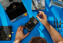 Apple expands repair options by supporting genuine used parts Technician repairing smartphone on blue workbench.