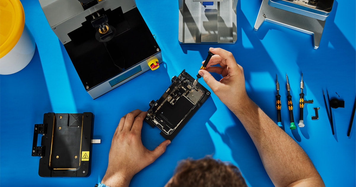 Technician repairing smartphone on blue workbench.