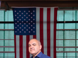Carlos Garcia-Galan Appointed Deputy Manager of NASA’s Gateway Program Carlos Garcia-Galan poses in front of the American flag in the Electric Propulsion and Power Laboratory at NASA’s Glenn Research Center. He has a serious expression is wearing a blue long-sleeve shirt with the Artemis program logo and black pants.