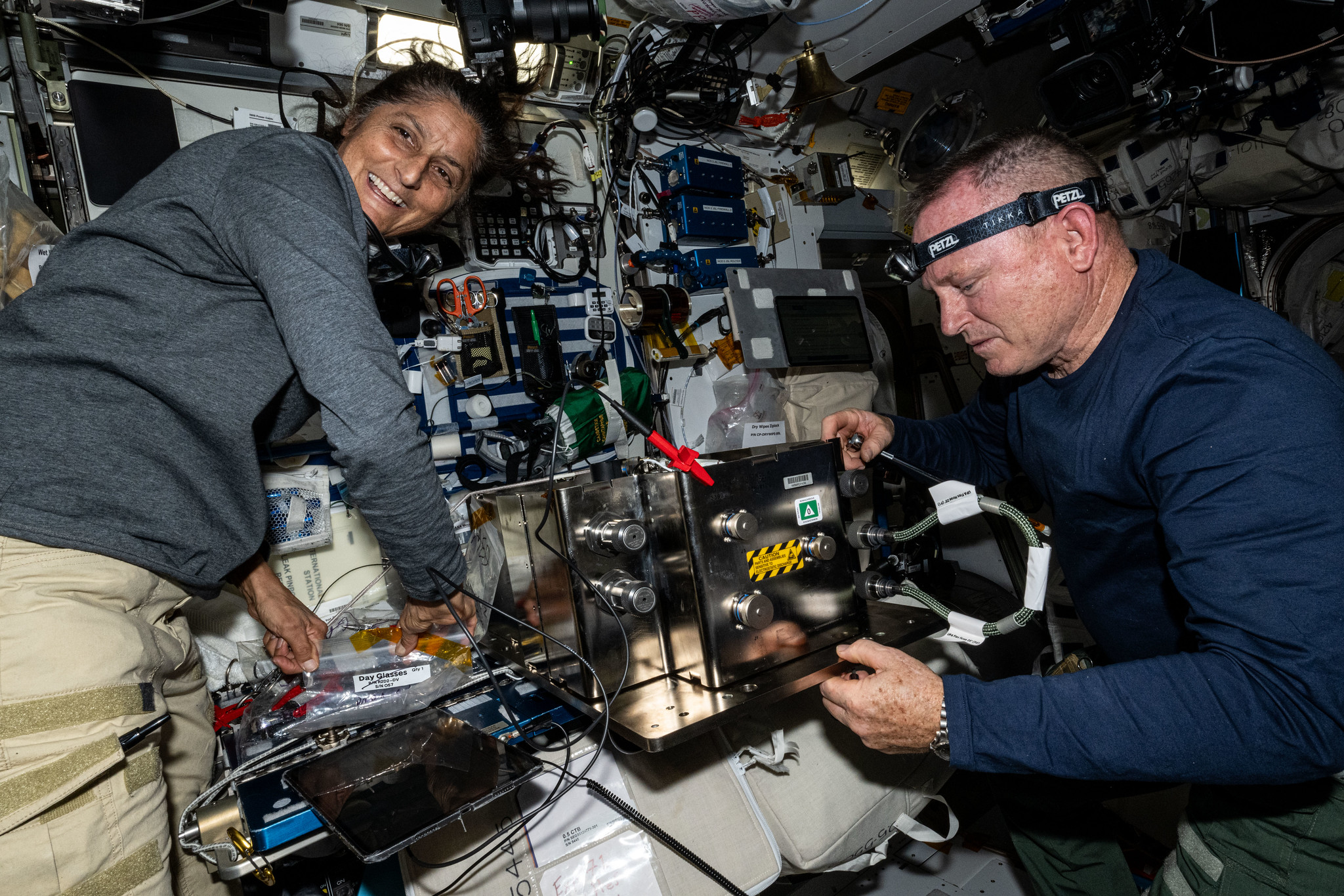butch and suni smaller.jpg NASA astronauts Butch Wilmore and Suni Williams prepare orbital hardware for installation inside the International Space Station.
