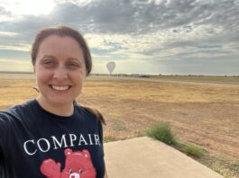 Regina Caputo Shapes the Future of High-Energy Astrophysics at NASA Regina Caputo smiles at the camera in a selfie that captures her head and shoulders. Her brown hair is tied back in a ponytail, and she is wearing a navy-blue tee-shirt which reads “COMPAIR.” Behind Regina is a large open field covered in patches of light brown and yellow grass. The sky is a hazy gray-blue and is covered in dark gray clouds that are thick in certain places but patchy. In the far distance behind Regina, nearing the horizon, is a large space-balloon. The balloon resembles a gray upside-down teardrop, the tip of which just touches the ground.