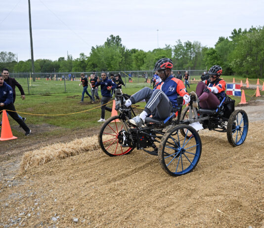 NASA Reveals Competitors for Global Rover Challenge Two students from Team Instituto Tecnologico de Santo Domingo from Santo Domingo, Dominican Republic, pedal their human-powered rover through the 2024 Human Exploration Rover Challenge course. Their teammates cheer them on from outside of the course.