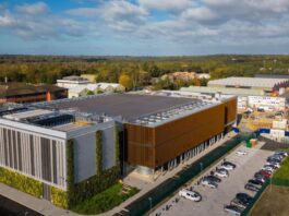 AI Factories’ Power Flexibility Stabilizing Global Energy Grids Image of Nebius AI factory in the UK surrounded by a parking lot and green foliage.