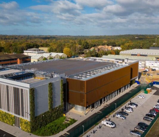 AI Factories’ Power Flexibility Stabilizing Global Energy Grids Image of Nebius AI factory in the UK surrounded by a parking lot and green foliage.