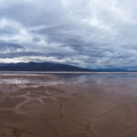NASA Identifies Human-Induced Changes in Worldwide Water Cycle A shallow pool of water over a cracked valley floor underneath a cloudy sky.