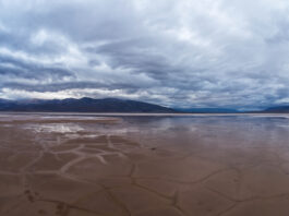 NASA Identifies Human-Induced Changes in Worldwide Water Cycle A shallow pool of water over a cracked valley floor underneath a cloudy sky.