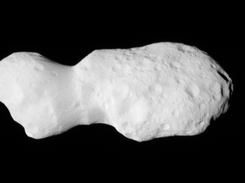 djencounter movie release v2.gif Gif of Asteroid Donaldjohanson, as seen by the Lucy spacecraft during its close flyby. The asteroid looks like two lobes, attached by a thinner cylinder, like a barbell with very large weights. One lobe is smaller than the other. Although they are both about the same circumference, the smaller lobe is less wide than the other. The asteroid is a smooth, light gray surface, with smooth-edged craters dimpling its surface. The larger lobe has many more craters. The asteroid moves closer to the camera, pushing in on the larger lobe. Then it rotates slightly to look along the asteroid long-ways.