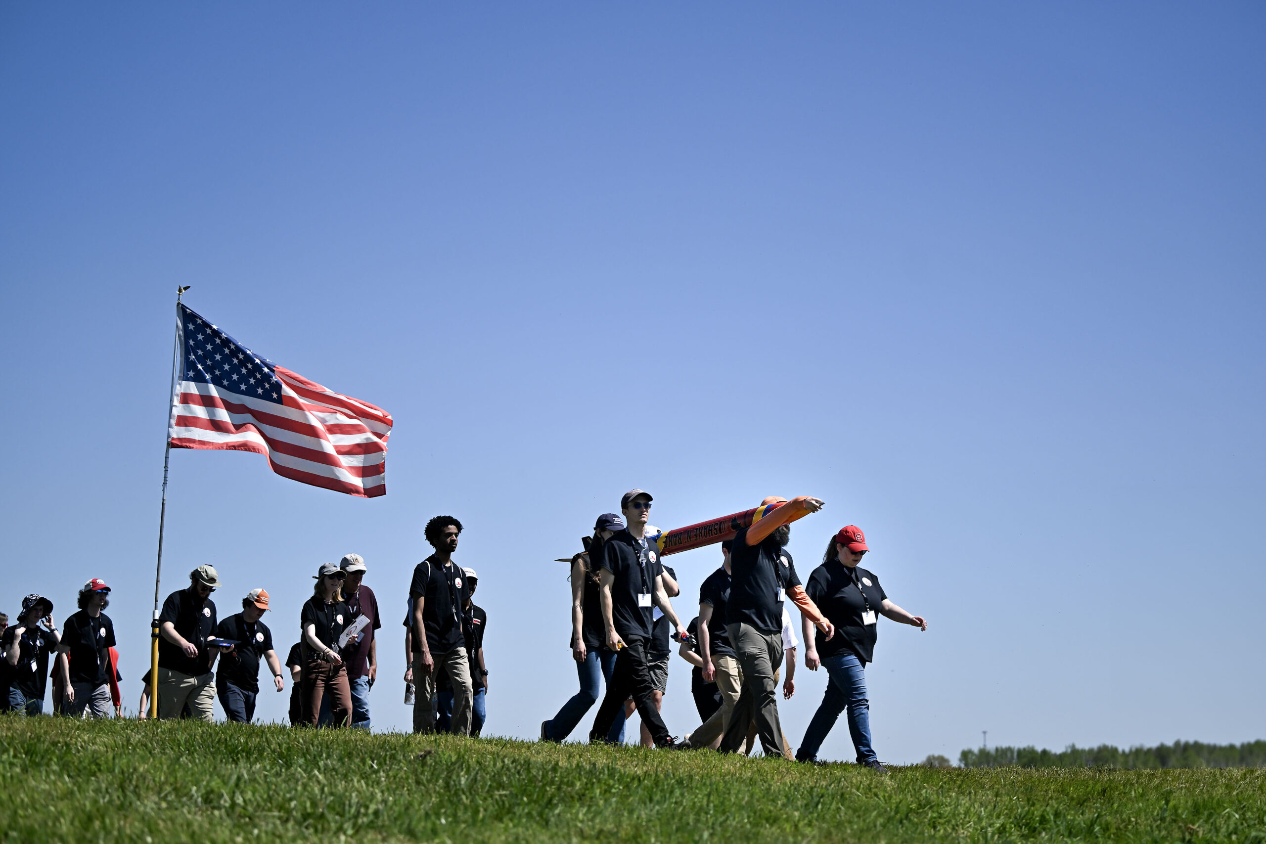 dsc 5853.jpg A group male and female students walk along a grassy field in Huntsville, Alabama with a Rocket as part of NASA
