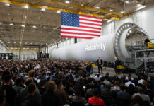 NASA Forms Partnership with Private Sector to Boost Mars Research NASA Administrator Jared Isaacman stands in front of a large, cylindrical, gray spacecraft with a white Relativity logo on it and addresses hundreds of Relativity Space employees. A large American flag hangs from the ceiling.