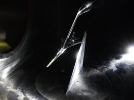 NASA Evaluates the X-59 Aircraft A scaled model of the X-59 experimental aircraft is inside a wind tunnel for testing. All of the visible surfaces and the plane are a metallic silver. The aircraft has a distinctive long nose with a curved end. A spotlight on the floor in the far corner lights up the scene.