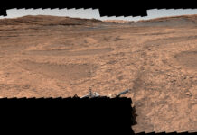 NASA’s Perseverance and Curiosity Showcase Stunning Mars Panoramas A series of shallow, sand-filled pits with low ridges spread across a tawny Martian landscape. Rover tracks stretch toward the horizon at left, and steep ridgetops loom in the background.