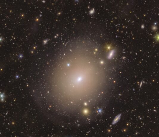NASA’s Euclid Unveils Einstein Ring Close to Earth A sea of colorful stars and galaxies appear to swim in the vast blackness of space around a hazy halo at centre stage. In the middle of the image, the fuzzy-looking bulb of light in a warm shade of yellow extends around a small bright spot, nestled within a thin light circle that appears to be drawn closely around it. As we follow the central halo’s rim outwards, its brightness dims and blends smoothly into its surroundings. Here, extended discs of shades ranging from a warm purple to golden yellow, and piercing dots of light with sharp diffraction spikes are spread evenly across the image.