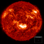 NASA’s Insights from Major Geomagnetic Storm in Two Decades A detailed, fiery image of the Sun showing bright solar flares and textured surface, with a small inset at the bottom right comparing the tiny size of Earth to the massive scale of the Sun.