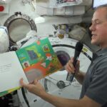 NASA Collaborations Ignite Worldwide STEM Education Initiatives NASA astronaut Thomas Marshburn, holding the book