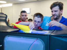 NASA Glenn’s Aviation Day Inspires Students to New Heights A researcher assists a student in guiding his cylindrical-shaped paper model into a tabletop demonstration unit.